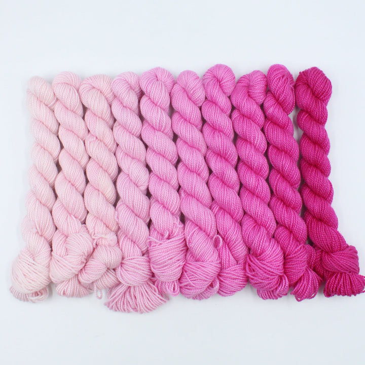 Stack of pink yarn with a gradient from light to dark on a white background
